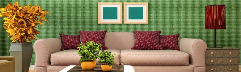 a sofa with red cushions and two plant pots on a coffee table