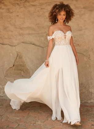 Bride in front of a stone wall. Gowns & Garters bridal shop in Thrapston Northants