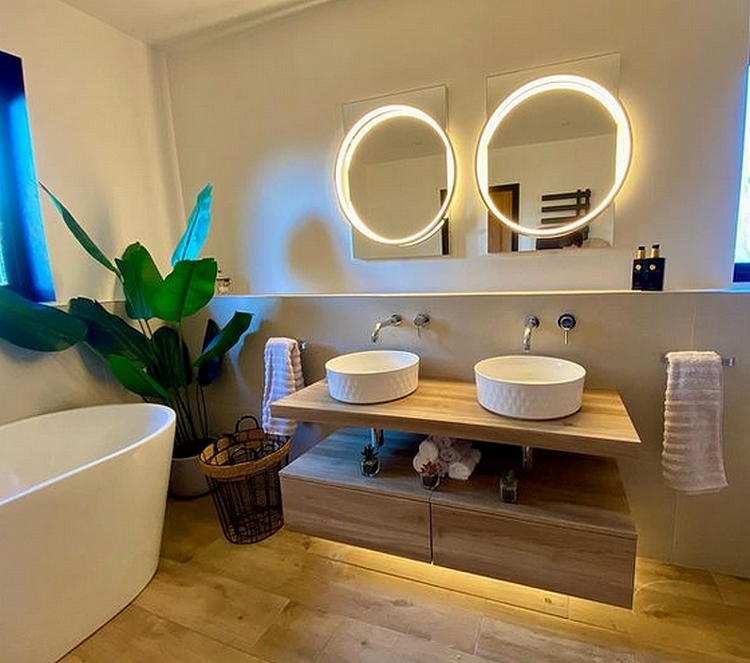 a bathroom with two basins, mirrors on the wall, and a bath