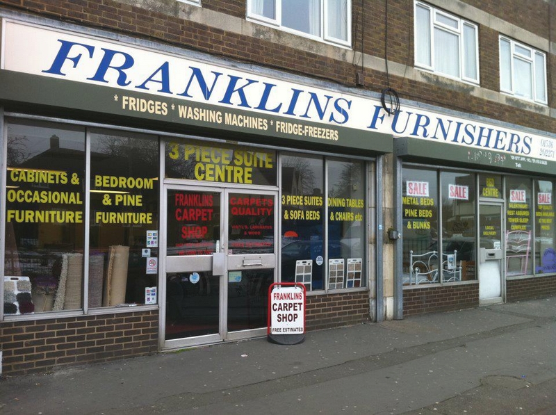 the front of a furniture shop with lots of signs in the window and an A board on the pavement