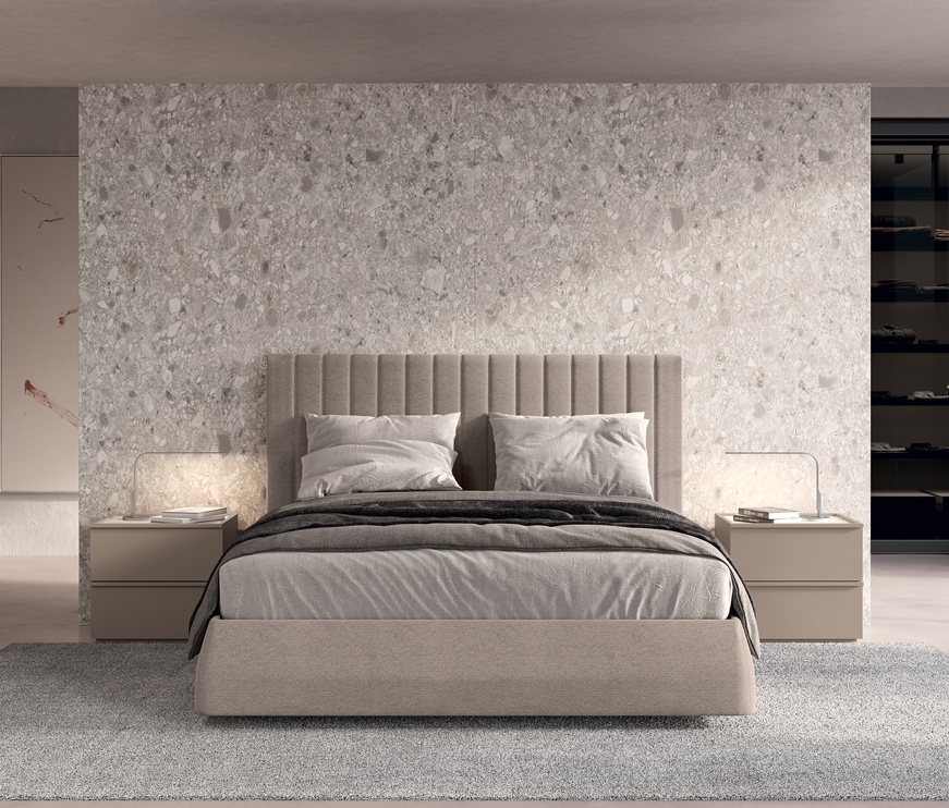 a double bed with neutral coloured bedding and a bedside on either side