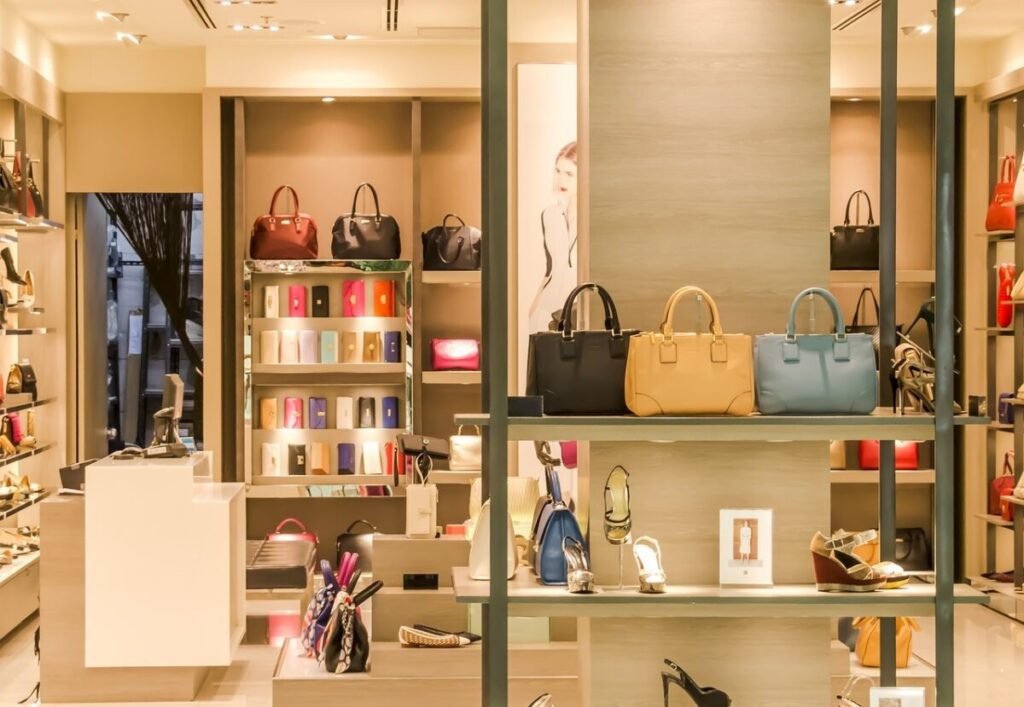 the inside of a shop selling handbags with handbags on shelves and some shoes