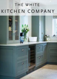 a grey blue kitchen with a white worktop and glazed wall units. Kitchens in Northampton. 