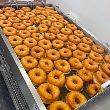 lots of doughnuts in a fryer cooking